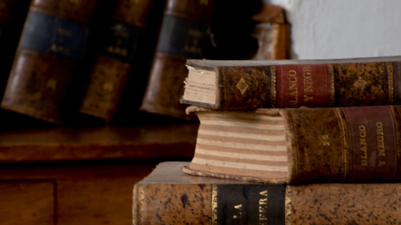 Stack of hardbound books on a wooden desk
