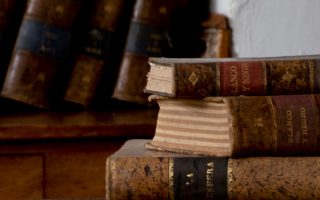 Stack of hardbound books on a wooden desk
