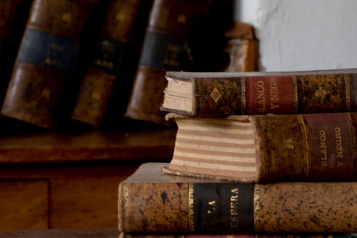 Stack of hardbound books on a wooden desk
