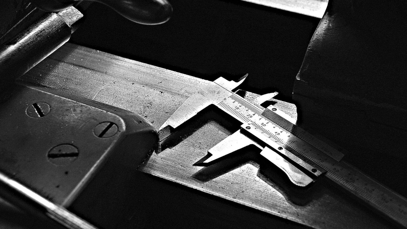 Black-and-white close-up of a caliper on a workshop table