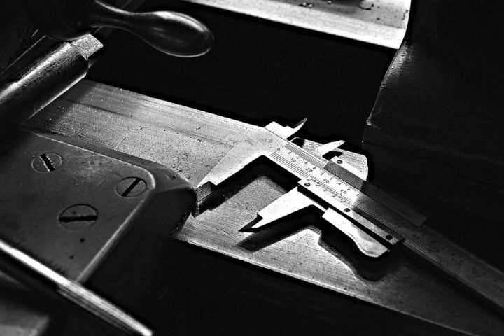 Black-and-white close-up of a caliper on a workshop table