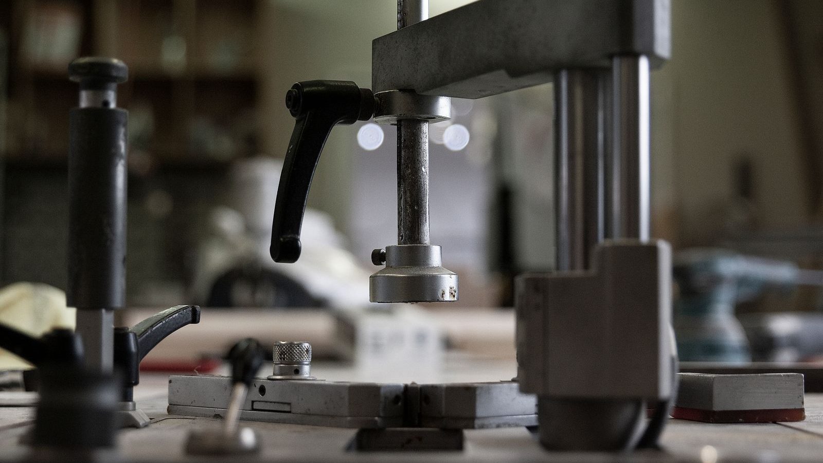 Bench-mounted machine with a steel column and lever in a workshop